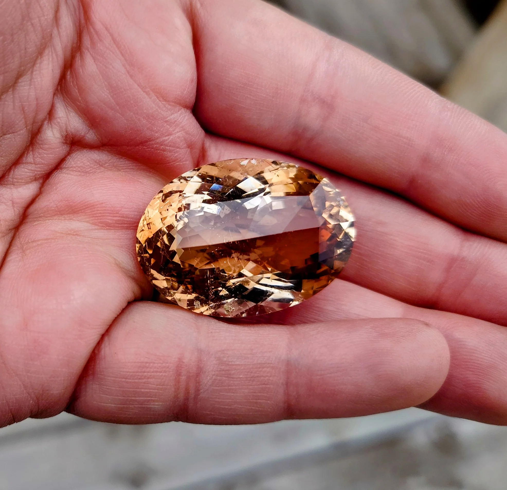 Oval imperial topaz displayed in the palm of a hand